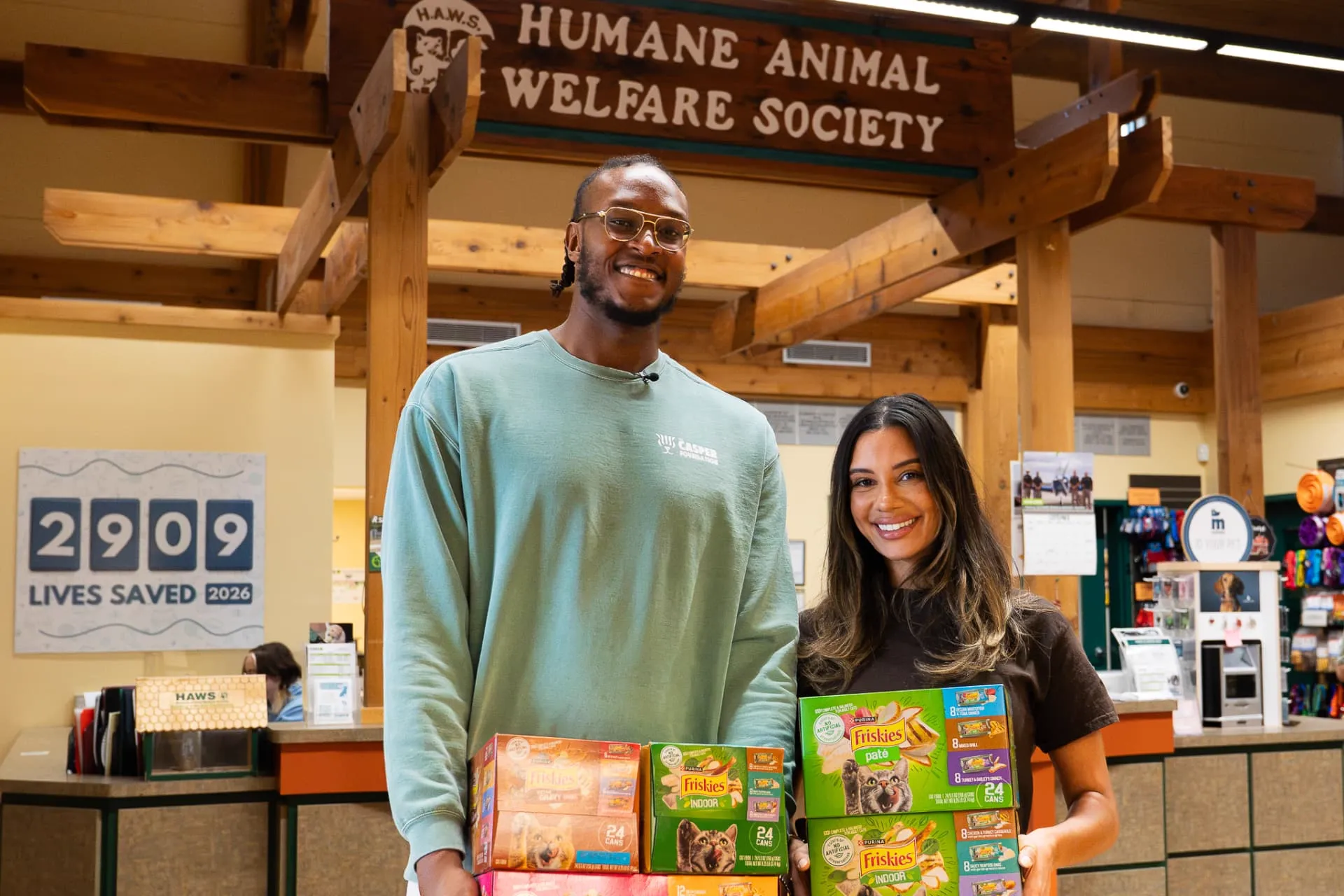 Myles and Aysia holding boxes of Friskies wet food at HAWS